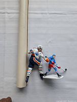 Growth chart partially rolled next to two Wayne Gretzky hockey figurines, showing size comparison and condition