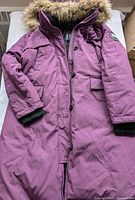 Front view of purple winter parka coat with fur trimmed hood laid flat
