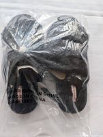 Slippers inside original clear plastic packaging with visible fabric texture and label.