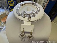Clear crystal bracelet displayed with matching drop earrings featuring gold-tone hooks and clear beads.