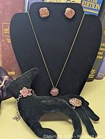Photo of the complete 4-piece jewelry set displayed on black holders including ring, earrings, bracelet, and necklace with pendant.
