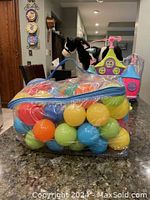 Clear plastic zippered bag filled with a variety of colorful plastic balls including yellow, blue, green, orange, and red, placed on countertop indoors.