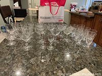 Various crystal glasses on dark granite countertop arranged in rows showing different styles and patterns.