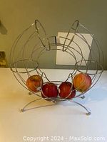 Front view of the metal wire fruit holder with apples inside, shaped like a sitting cat.