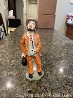 Photo of doctor figurine standing on a granite countertop, showing front view with orange suit and hat.