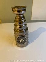 Image of a silver metallic replica Stanley Cup hockey trophy with detailed bands and Toronto Maple Leafs emblem on the base