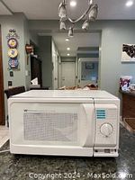 Front view photo of a white Whirlpool microwave oven with mesh screen window and mechanical dial controls on the right side.