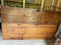 Stained pine tabletop leaning against shed wall