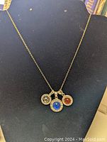 Front view of the 20-inch sterling silver necklace displayed on a black surface showing the three pendants with blue, red-orange, and silver-tone crystals.