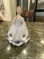 Front view of Royal Doulton figurine showing lady in white dress with blue floral patterns