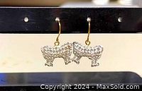 Photo showing one pair of bow-shaped earrings with clear Swarovski crystals and gold plated hooks, hanging on a display stand.