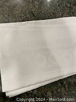 Folded white tablecloth showing subtle woven ornamental patterns in white