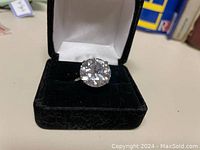 Front view of the silver ring with a large round cubic zirconia in black velvet box.