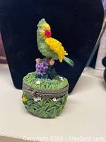 Front view of the closed parrot-themed trinket box showing detailed colorful parrot figure on top and surrounding foliage design.