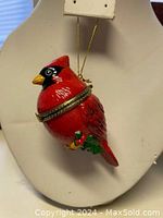 Front view of the red cardinal trinket box with gold-tone chain displaying detailed paint and clasp.