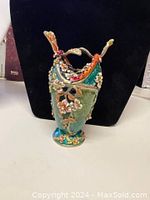 Green basket trinket box with gold and floral details, red Swarovski crystals, and basket handles, front view showing closed top