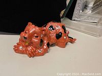 Closed orange ceramic sleeping dog trinket box with black spots.