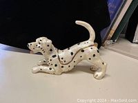 Side view of ceramic Dalmatian dog trinket box showing body and gold rim hinge.