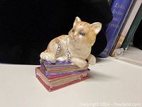 Orange cat trinket box on purple, yellow, and red books, showing the front and cat details