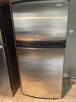 Front view of closed refrigerator showing stainless steel finish and dent on freezer door