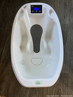 Full view of white plastic baby bathtub with head-end digital scale display and contoured seating area.