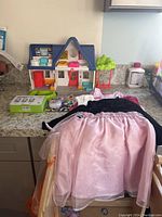 Photo of Little People house playset, three girls' dresses, and Baby Einstein toy on kitchen counter