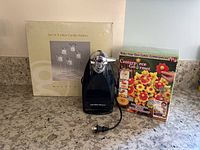 Photo of all three items together on kitchen counter showing candle holders box, electric can opener, and edible centerpiece maker kit box.