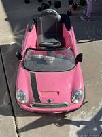 Front angle view of pink Mini Cooper kids electric car showing hood, windshield, and steering wheel.