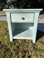 Front view showing light blue painted nightstand with single drawer and open shelf.