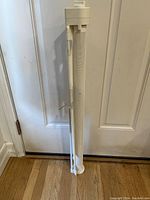 Retractable white mesh pet gate rolled up and standing upright against a door.