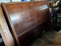 Curved sleigh style headboard with polished wood surface and visible grain.