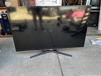 Front view of Samsung 48-inch flat-screen television with black curved stand on concrete floor.