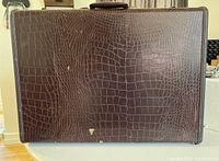 Top view of the vintage brown suitcase showing crocodile pattern exterior with wear marks and chips.