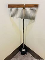 Front view of chime stand showing metal tubes hanging from wooden bar attached to a chrome pole with a black square base