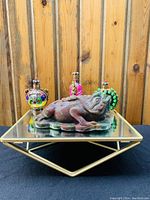 Front view of the jade 3-legged toad figurine with the three cloisonné bottles positioned behind it on a mirror surface, showing details on the frog's head and the vibrant colors of the bottles.