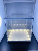 Front view of the clear acrylic light box display cube showing LED lighting inside base.