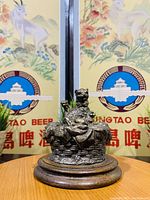 Front view of the antique brass Victorian inkwell depicting a cat figure on a woven basket design, placed on round wooden base.