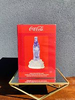 Front view of the red box packaging for the Coca-Cola bottle lamp, showing branding and product photo.