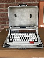 Open typewriter in its carrying case showing keyboard and ribbon area.