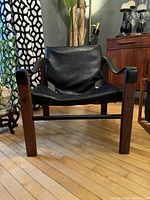 Front-on view of chair showing leather sling seat and teak frame