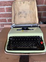 Front view of Olivetti Lettera 22 typewriter with open carrying case showing keys and interior of case.