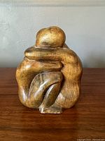 Front view of the hand carved hardwood sculpture showing the stylized embracing figures