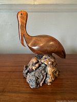 Front angled view of the carved teakwood pelican on natural base highlighting smooth carving and natural wood grain.