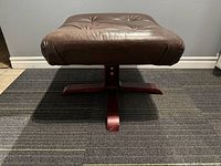 Front view of vintage brown leather ottoman showing seat and wooden base.