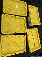 Five yellow 27 gallon storage tote lids stacked and laid out flat.