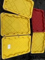 Photo showing multiple yellow and one red HDX plastic storage tote lids and tubs as the containers for the lot.