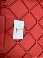 Red 27 gallon storage tote lid with a paper label marked '1'. Photo taken to show tote container and lot packaging size.