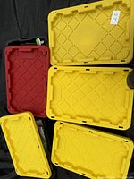 Photo showing five plastic storage totes with yellow and red lids, labeled lot 20.