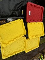 Five large 27 gallon plastic storage tote lids, four yellow and one red with number 4 label, showing the container lids for the lot.