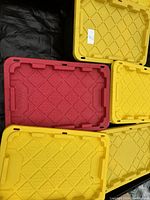 Photo of 5 durable plastic storage tote lids in yellow and red colors, stacked together.